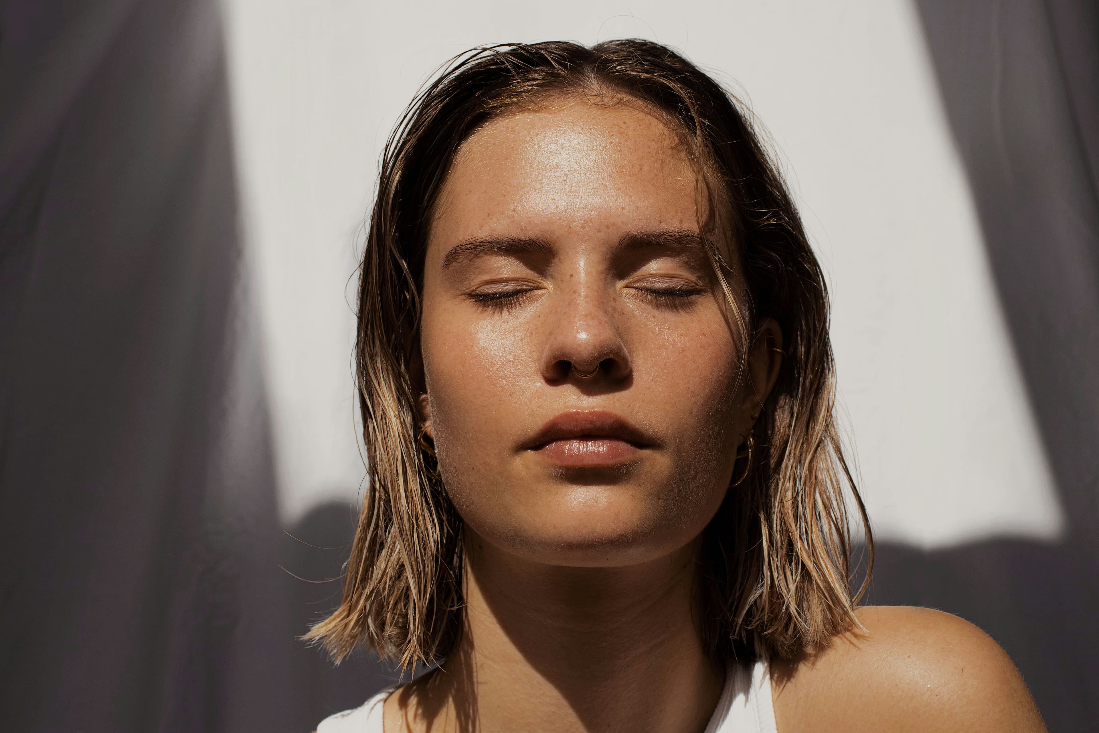 A luxurious, minimalist white skincare bottle with gold accents centered in a bright, ethereal studio setting.